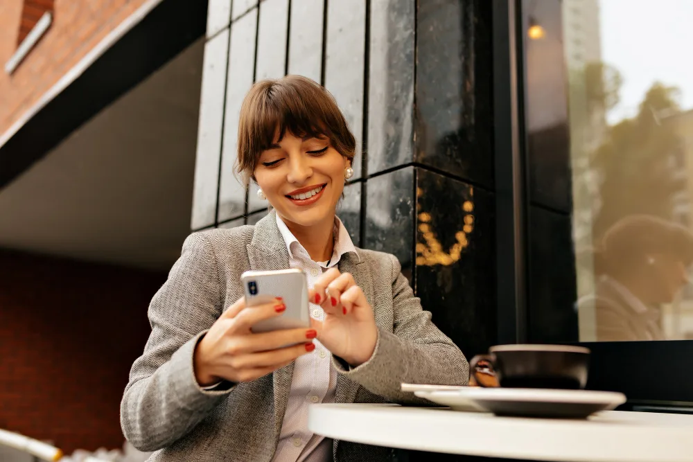 Investidora usando o celular em um café